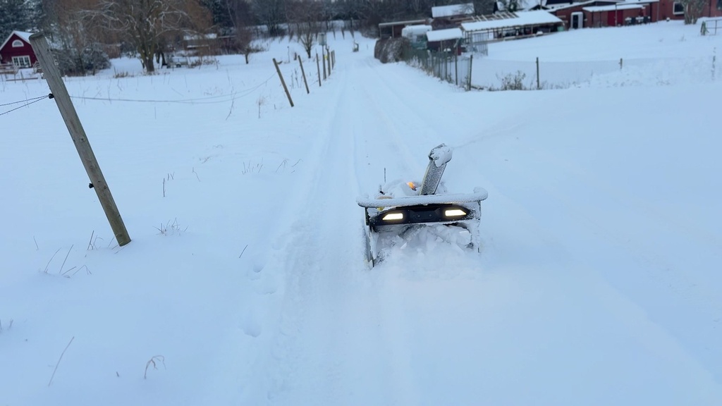 Nortec Explore X1 med snöslunga röjer en väg i djup snö, sedd bakifrån