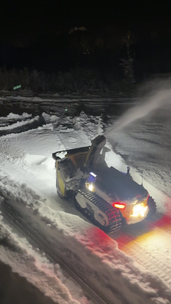 Nortec Explore X1 med snöslunga röjer på natten, med strålkastare och en båge av snö